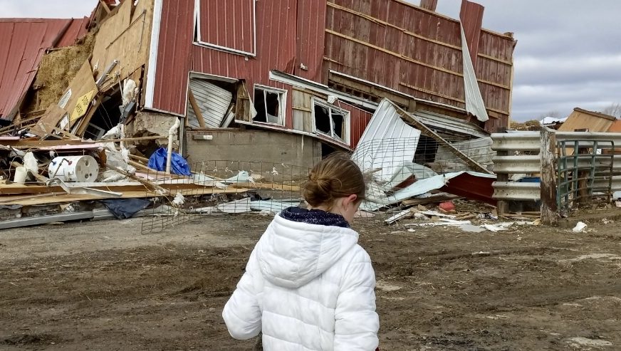 A young girl walking through the destruction of the recent tornado in WI