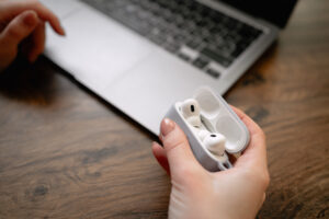 Close-up of female hands working remotely online in front of laptop, putting headphones in case after listening to music.